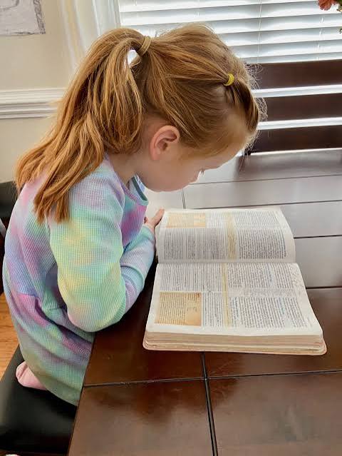 Child studying an open Bible